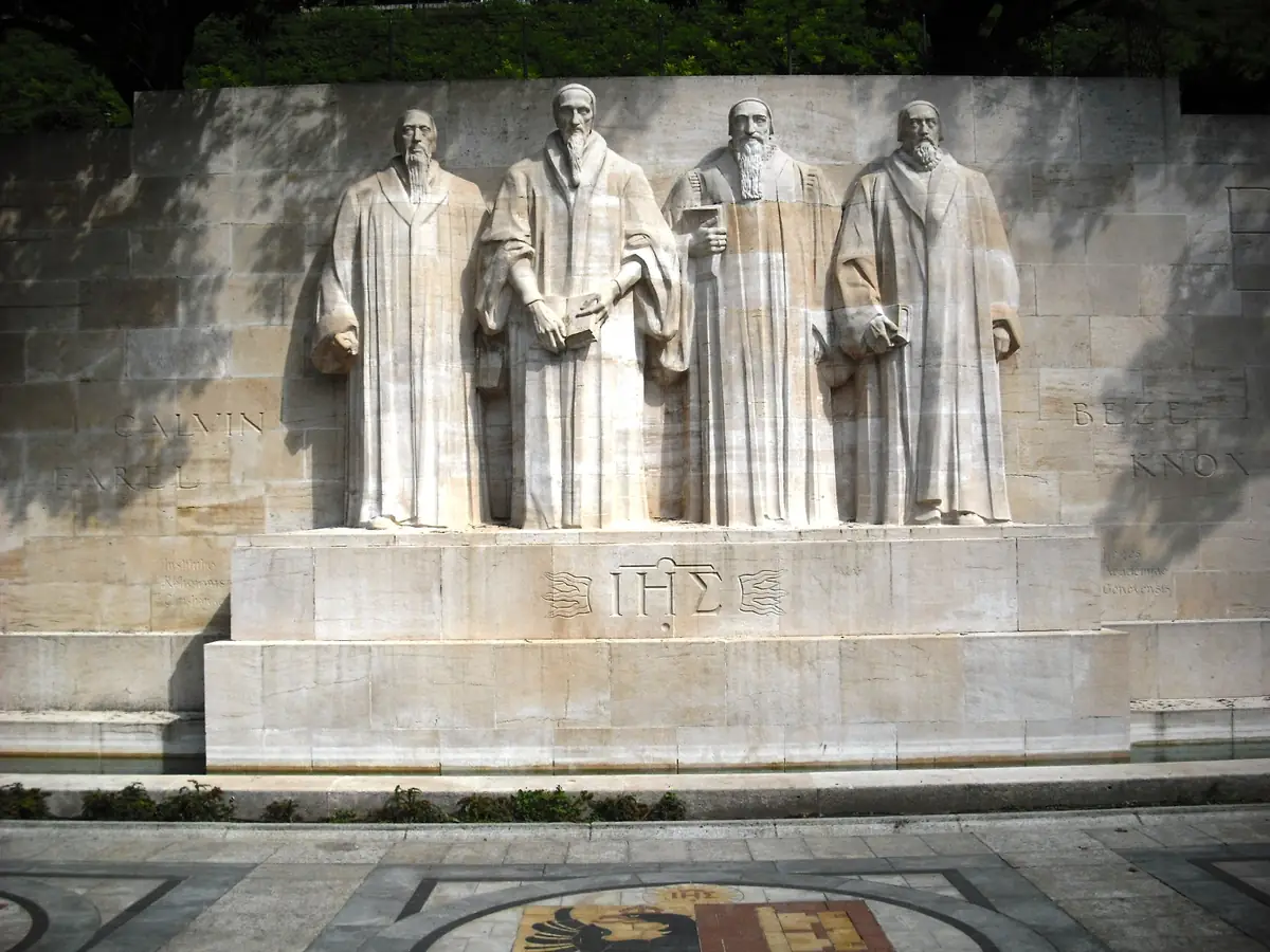 The Reformation Wall in Geneva: stone statues of William Farel, John Calvin, Theodore Beza, and John Knox.